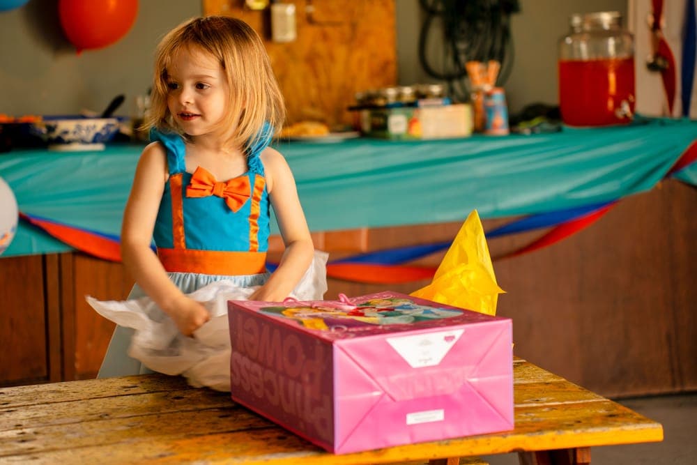 A young girl unwrapping a gift at a birthday party