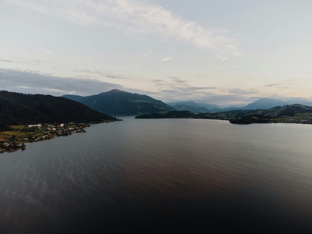 Aerial view of a calm lake surrounded by hills at dusk