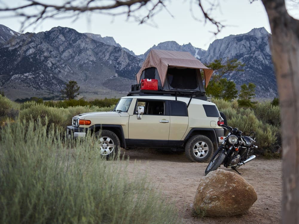 An off-road vehicle with a rooftop tent in the mountains