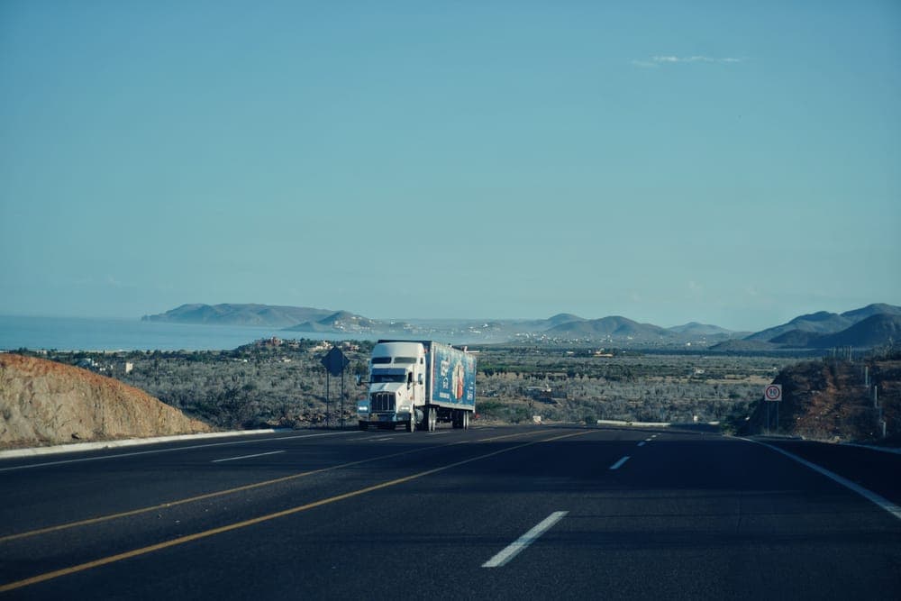 A semi-truck on a highway with mountains behind it