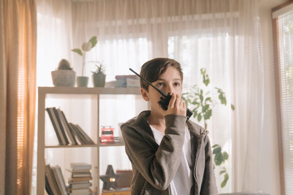 A boy at home talking into a toy-style walkie-talkie